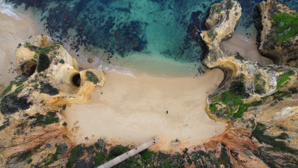 Panorama Praia do Camilo z widocznymi formacjami skalnymi i piaszczystą plażą