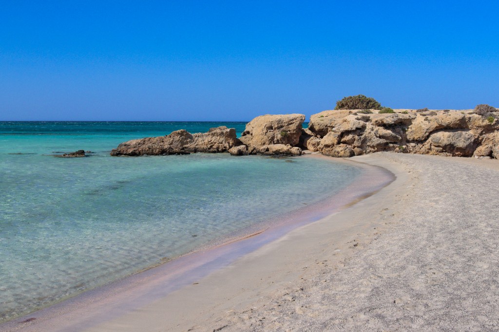 Elafonisi - przewodnik po różowej plaży Krety Zatoczka na plaży Elafonisi – różowy piasek i kamienie w wodzie