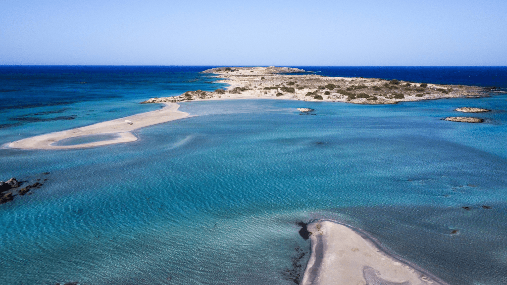 Elafonisi - przewodnik po różowej plaży Krety Laguna Elafonisi na Krecie widziana z lotu ptaka, turkusowa woda i piaszczyste wysepki.