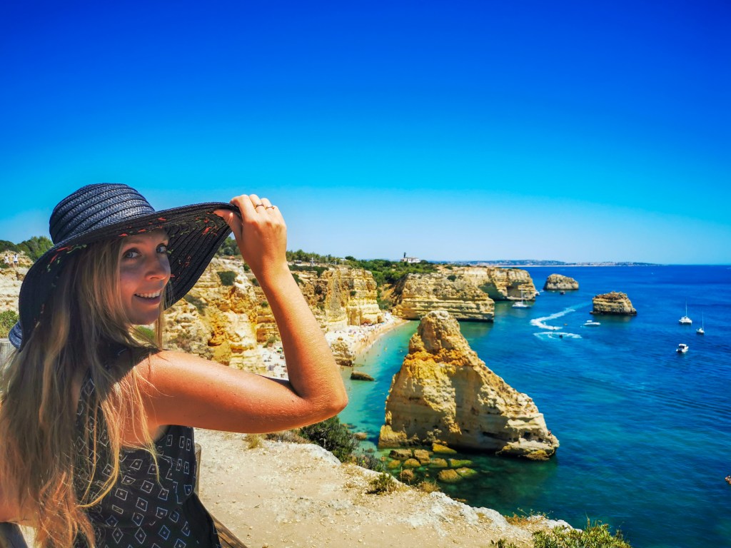 Kobieta w kapeluszu na tle Praia da Marinha w Algarve, panorama klifów i turkusowego morza