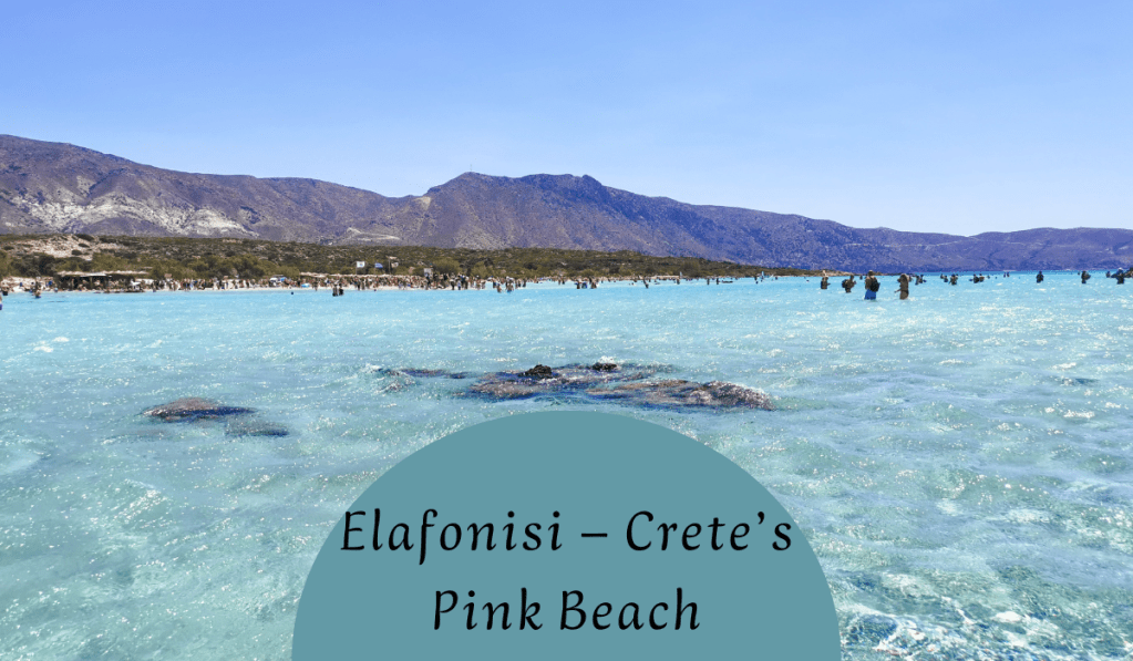 A scenic view of Elafonisi, Crete's pink beach, showcasing turquoise waters and a mountainous backdrop.