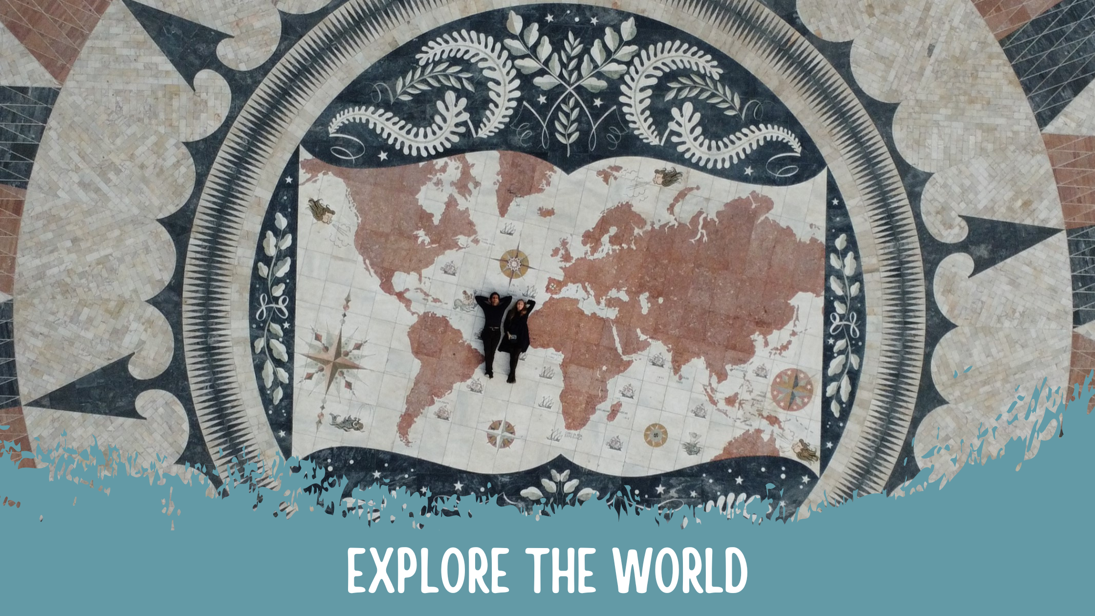 Aerial view of two people lying on a world map designed on a stone floor, with decorative elements surrounding the map and the phrase 'Explore the World' written at the bottom.