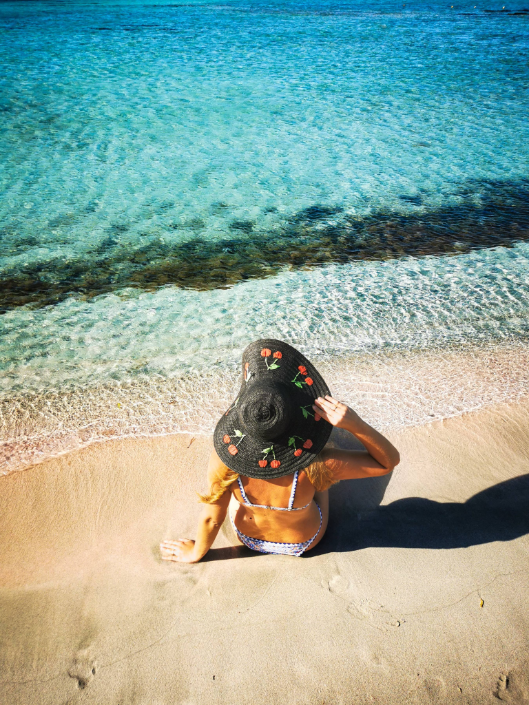 Elafonisi – Your Travel Guide to Crete’s Famous Pink Beach Woman in a hat relaxing on Elafonisi Beach – turquoise waters and pink sands