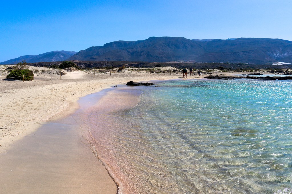 Elafonisi – Your Travel Guide to Crete’s Famous Pink Beach Beautiful Elafonisi Beach in Crete with pink sand, turquoise waters and mountains in the background