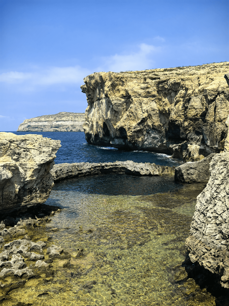 Exploring Gozo in One Day – What to See Clear blue water inside the Blue Hole rock pool surrounded by limestone cliffs and the Mediterranean Sea, Gozo, Malta
