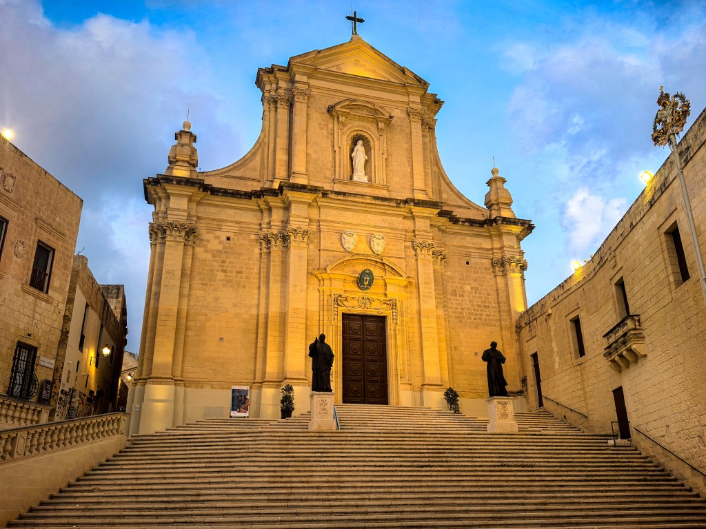 Fachada barroca imponente da Catedral da Assunção, escadaria e estátuas, iluminada ao entardecer, Cittadella, Gozo