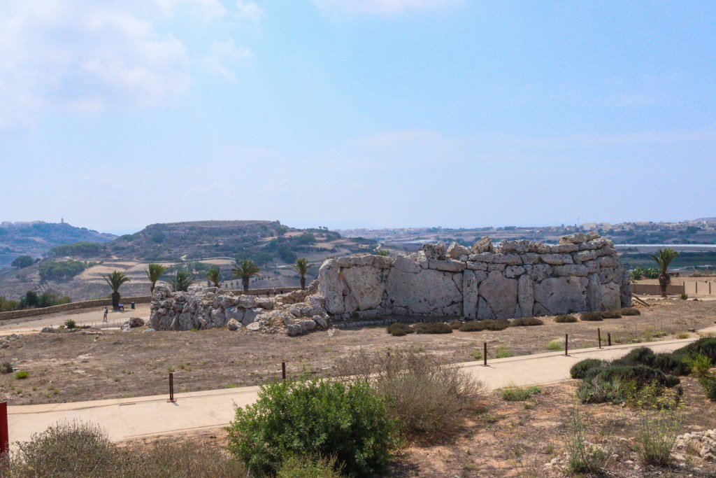 Vista panorâmica dos antigos templos megalíticos de Ġgantija, em Gozo, com paredes de pedra e paisagem rural de Malta ao fundo