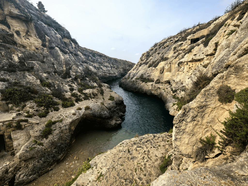 Vista panorâmica sobre o desfiladeiro profundo e as águas azuis de Wied il-Għasri, Gozo, Malta