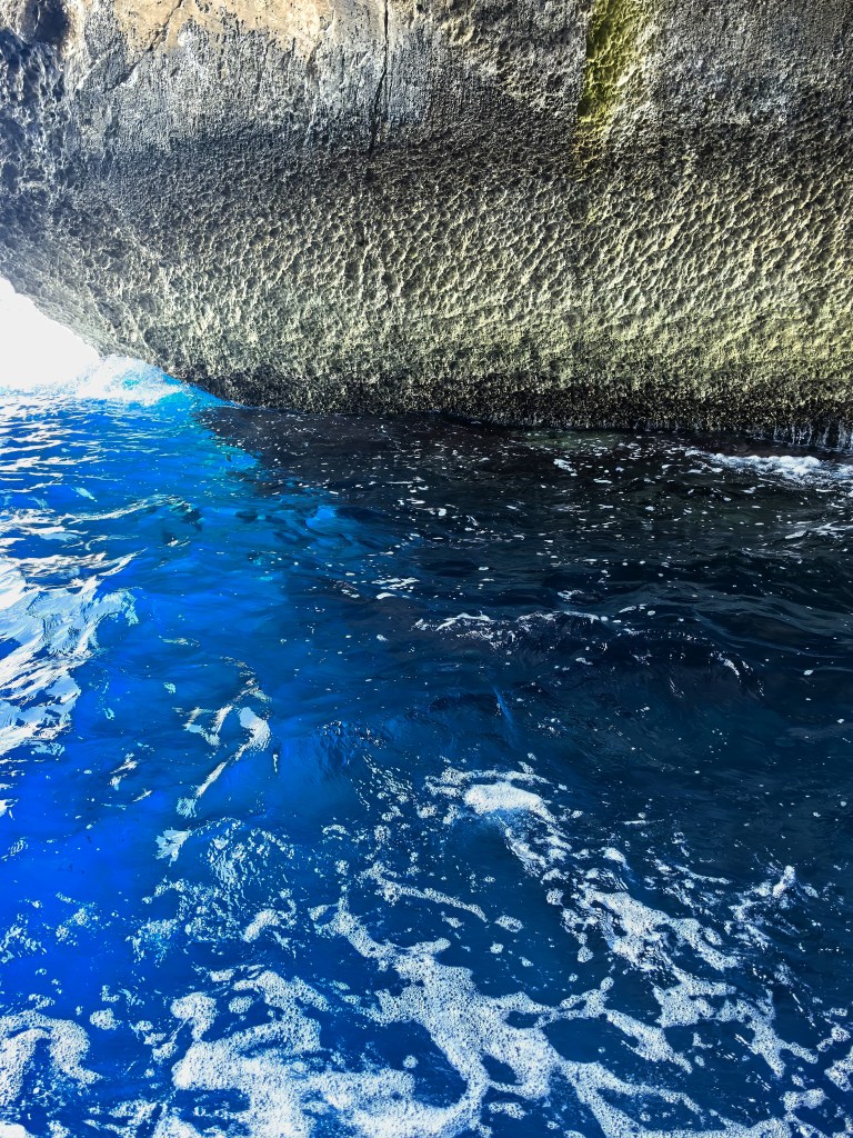 Exploring Gozo in One Day – What to See Vivid blue water at the mouth of a sea cave on Gozo, Malta, where sunlight illuminates the waves beneath limestone cliffs, Dwejra.