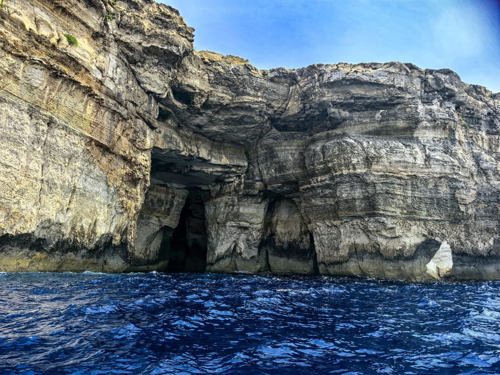 Wejście do monumentalnej jaskini morskiej w wapiennych klifach Gozo widziane podczas rejsu z Inland Sea