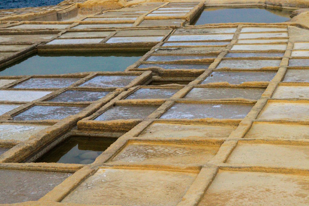 Tanques geométricos das salinas de Xwejni, Gozo, Malta, com cristais de sal a formar-se à superfície