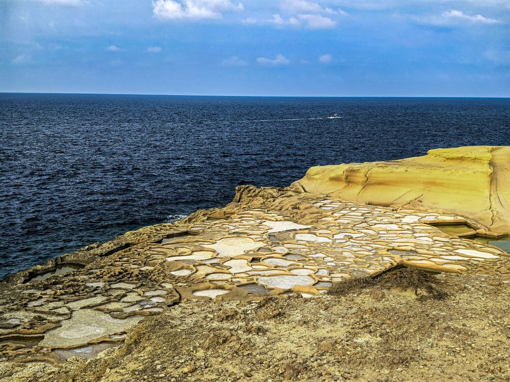 Exploring Gozo in One Day – What to See Geometric Xwejni Salt Pans on the rocky coast of Gozo, Malta, with the blue Mediterranean Sea on the horizon – historic Roman-era salt production site.