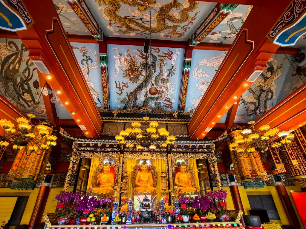 Altar dourado ornamentado com Budas, flores e decorações, interior do Mosteiro Po Lin, Hong Kong.