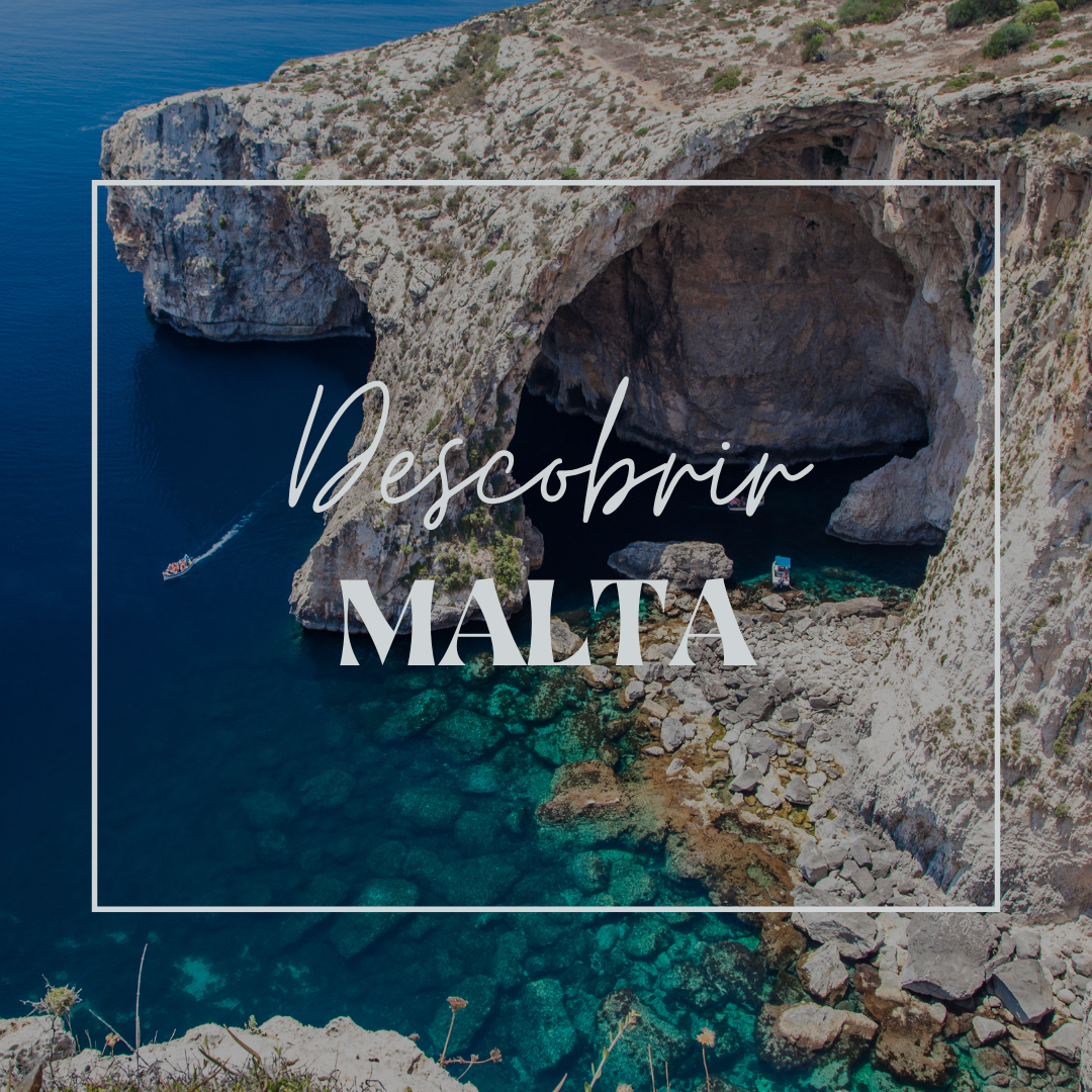 Vista panorámica de la costa de Malta con aguas cristalinas y una embarcación pequeña navegando cerca de una cueva en la roca.