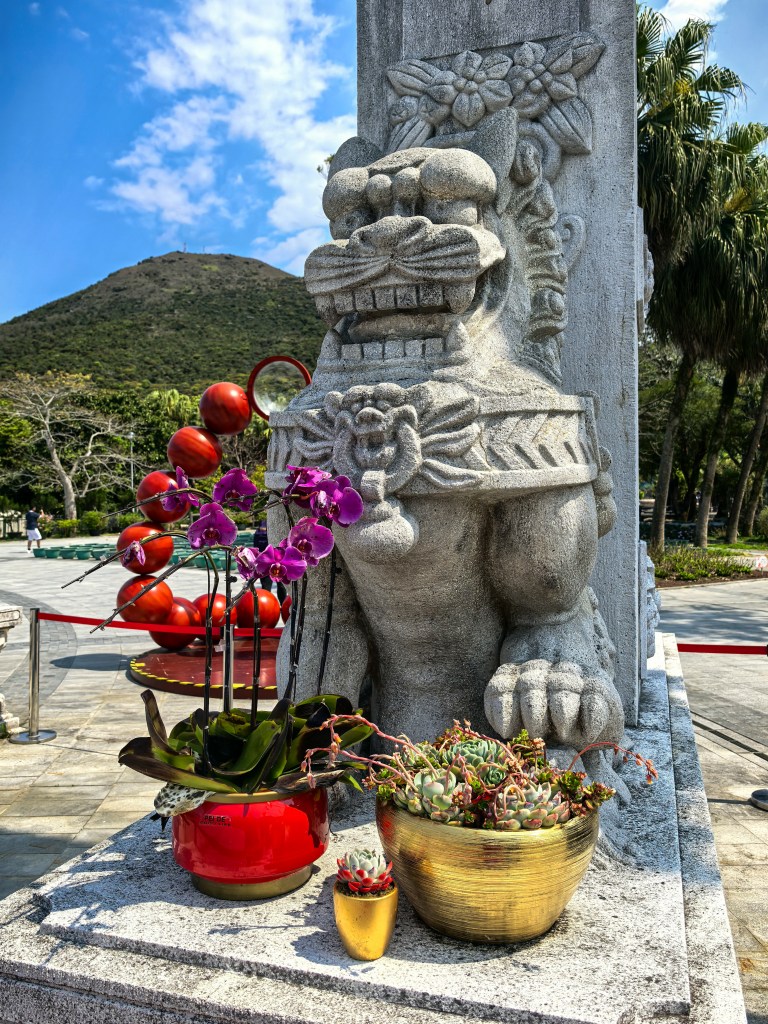 Estátua de leão de pedra decorativa com orquídeas em Ngong Ping, Ilha de Lantau, Hong Kong.