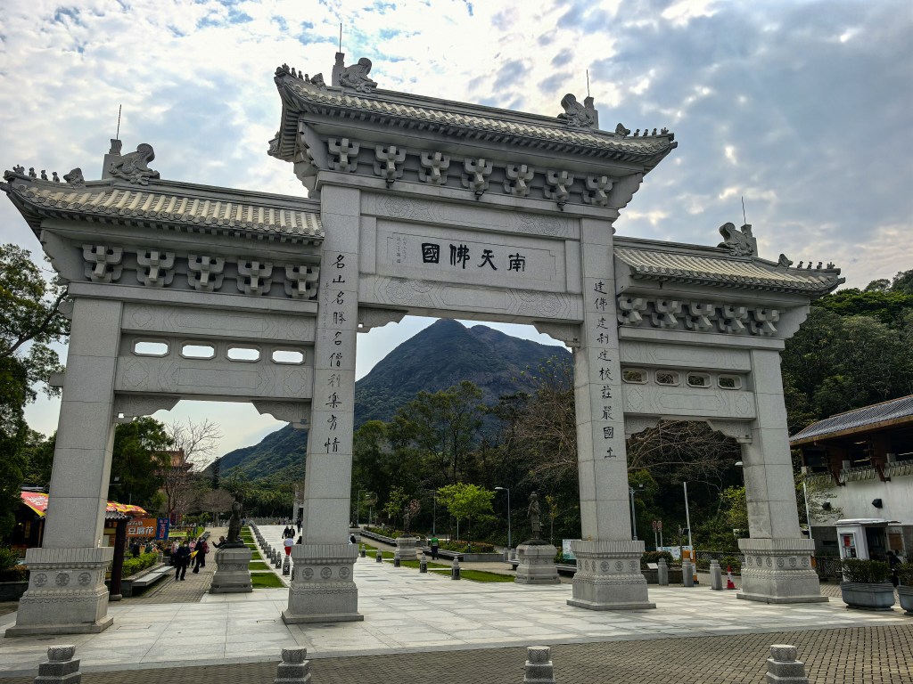 Stone entrance gate at Ngong Ping with mountain backdrop, near Tian Tan Buddha, Hong Kong.
