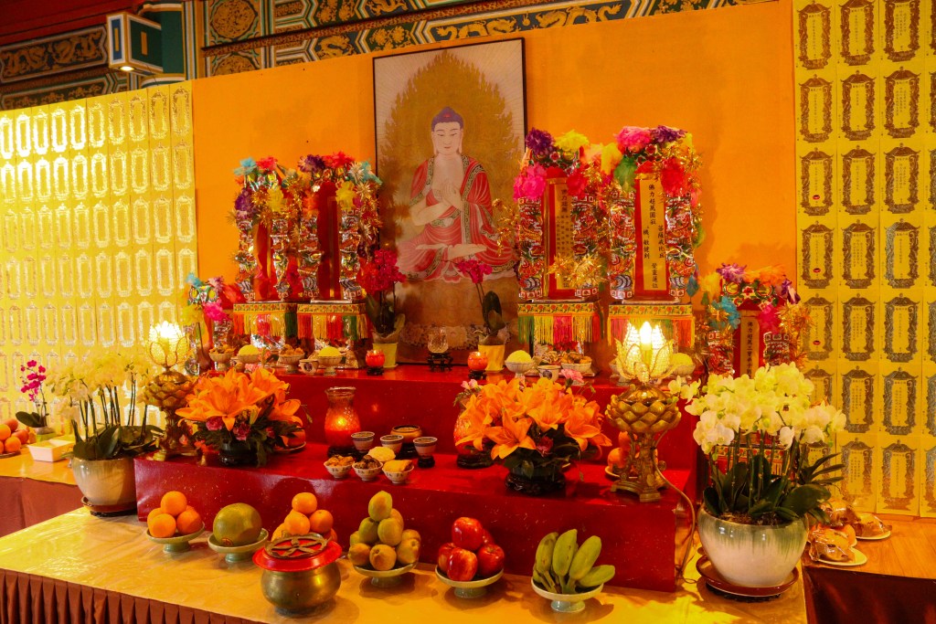 Altar festivo com frutas, flores e ofertas no interior do Mosteiro Po Lin, Hong Kong.