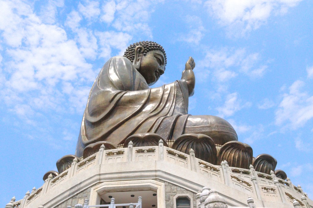 Side view of the Tian Tan Buddha statue against blue sky, Hong Kong.