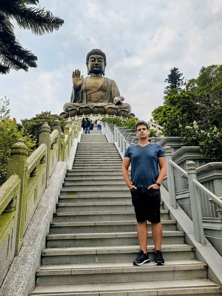 Man standing on stairs leading to Tian Tan Buddha statue, Hong Kong.