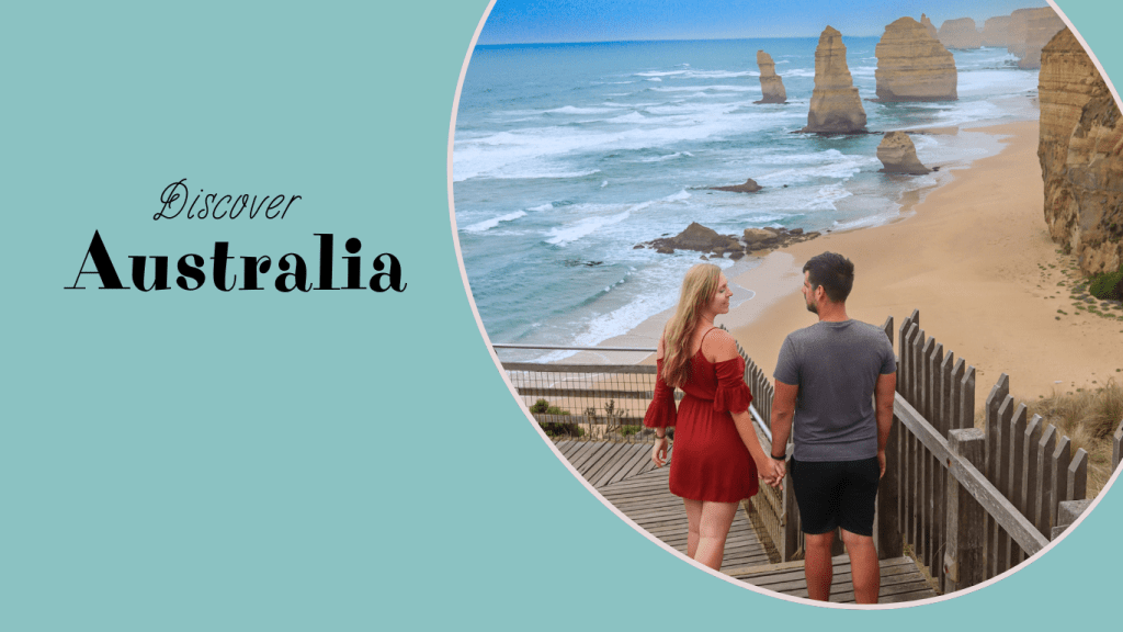 Para stojąca na drewnianym pomoście, patrząca na plażę z klifami w Australii, z napisem "Odkryj Australię".