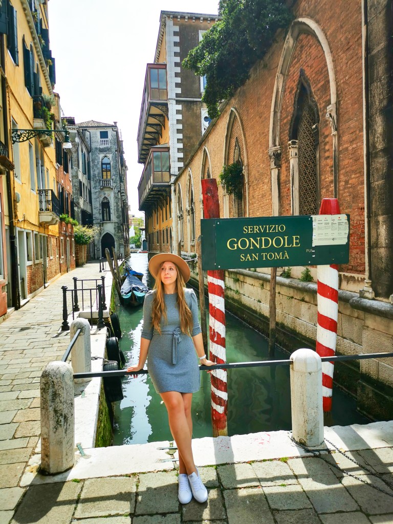 Venice: Everything You Should Know Before Your Trip Woman in grey dress at San Toma gondola station on a narrow Venice canal.