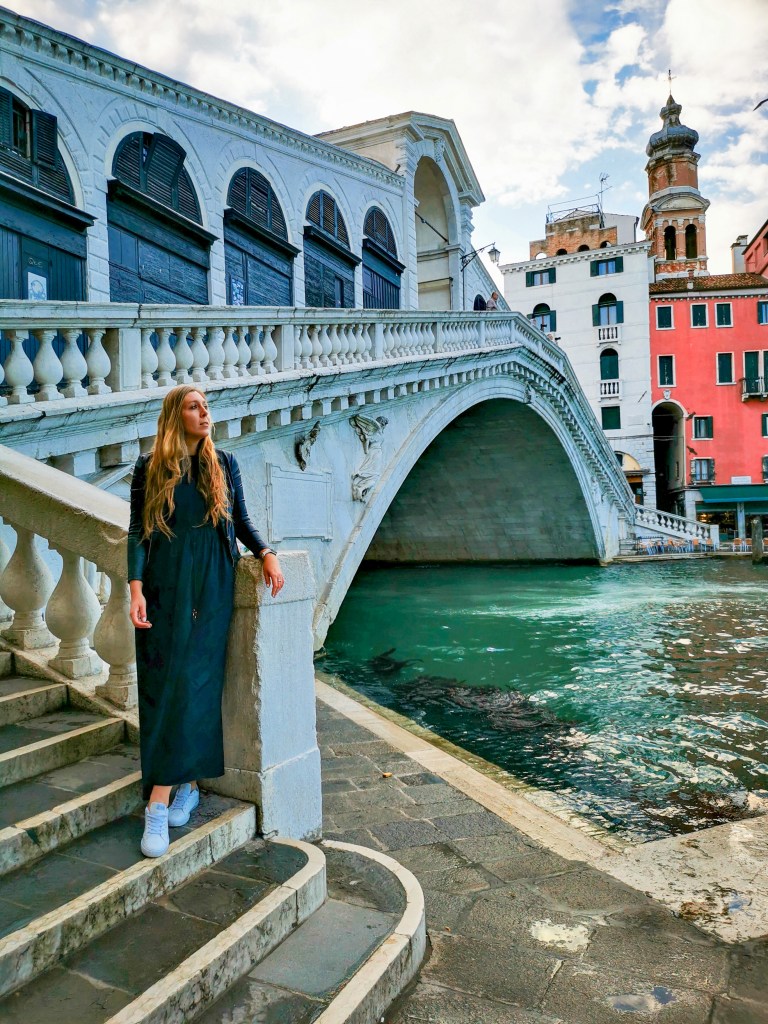 Venice: Everything You Should Know Before Your Trip Woman in long dress posing on the stairs by the Rialto Bridge on the Grand Canal in Venice.