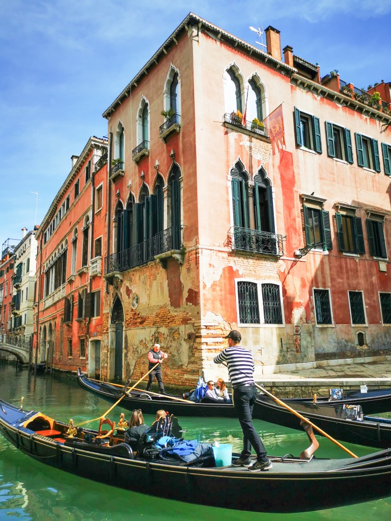 Gondole płynące kanałem wśród kolorowych kamienic Wenecji