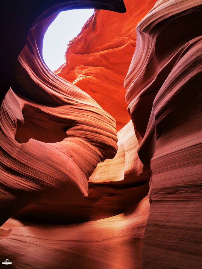 Tall sandstone walls inside Antelope Canyon in shape of woman's head with a bright opening above in Arizona
