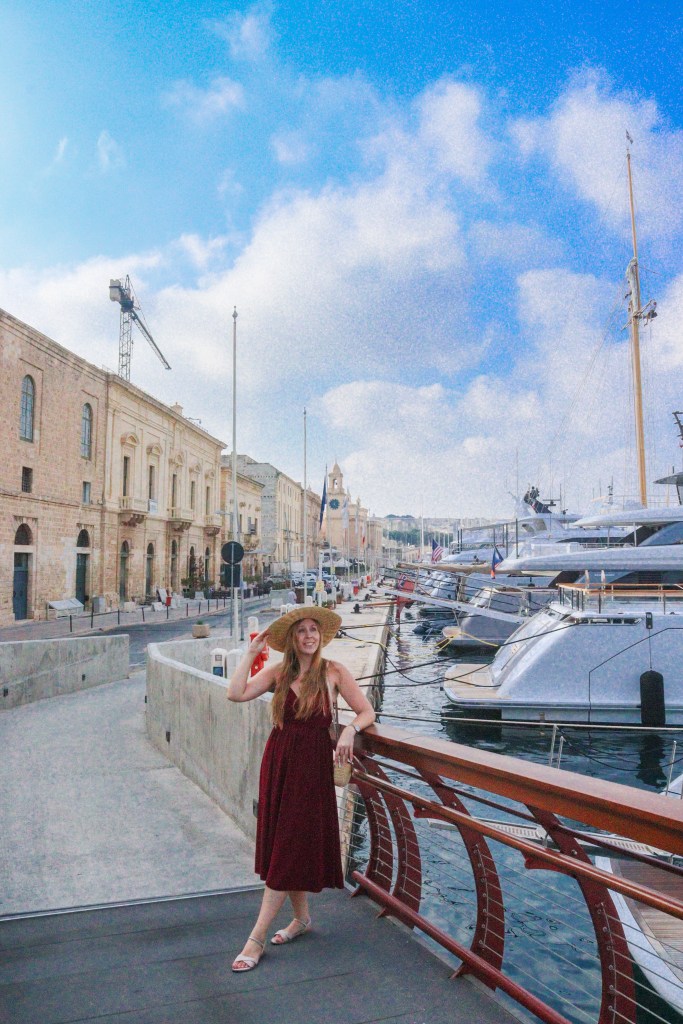 Podróżniczka w kapeluszu pozuje przy nabrzeżu z luksusowymi jachtami w Birgu, Trzy Miasta Malta.
