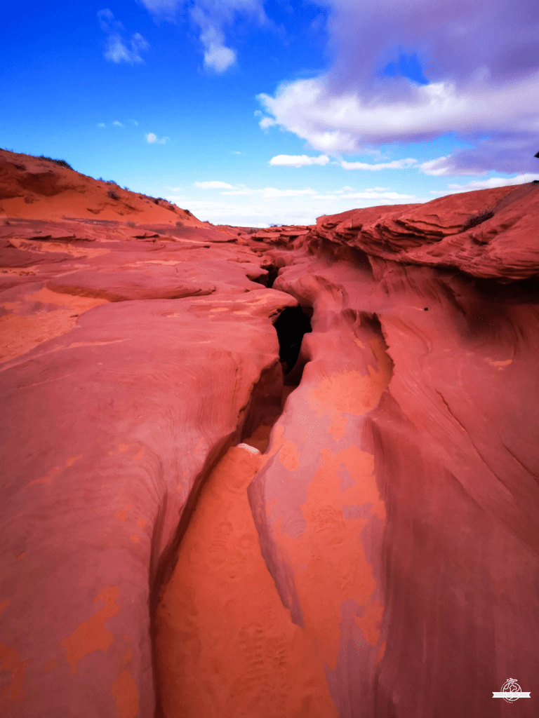 Opening of Antelope Canyon viewed from above with red sandstone and blue sky in Arizona