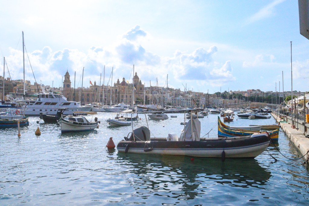 Łódki i jachty zacumowane w marinie Isli z barokowym kościołem i piaskowymi kamienicami Trzech Miast w tle.