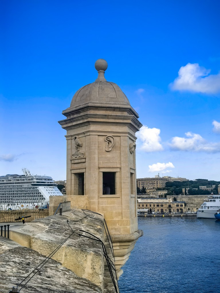 Kamienna wieża strażnicza Il-gardjola w Isli z widokiem na statek wycieczkowy i Vallettę nad Grand Harbour. Guardjola Gardens.