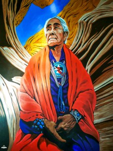Pintura mural vibrante de uma idosa Navajo com cabelo branco, envolta em manta laranja e colares turquesa, com formações rochosas do Antelope Canyon em tons vermelhos e céu azul ao fundo.