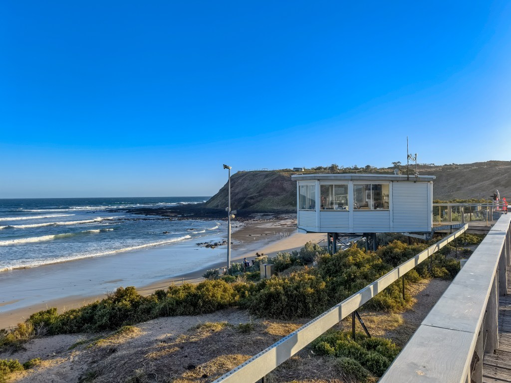 Elevated viewing building beside a boardwalk overlooking waves and a sandy beach near the Penguin Parade on Phillip Island, Australia.