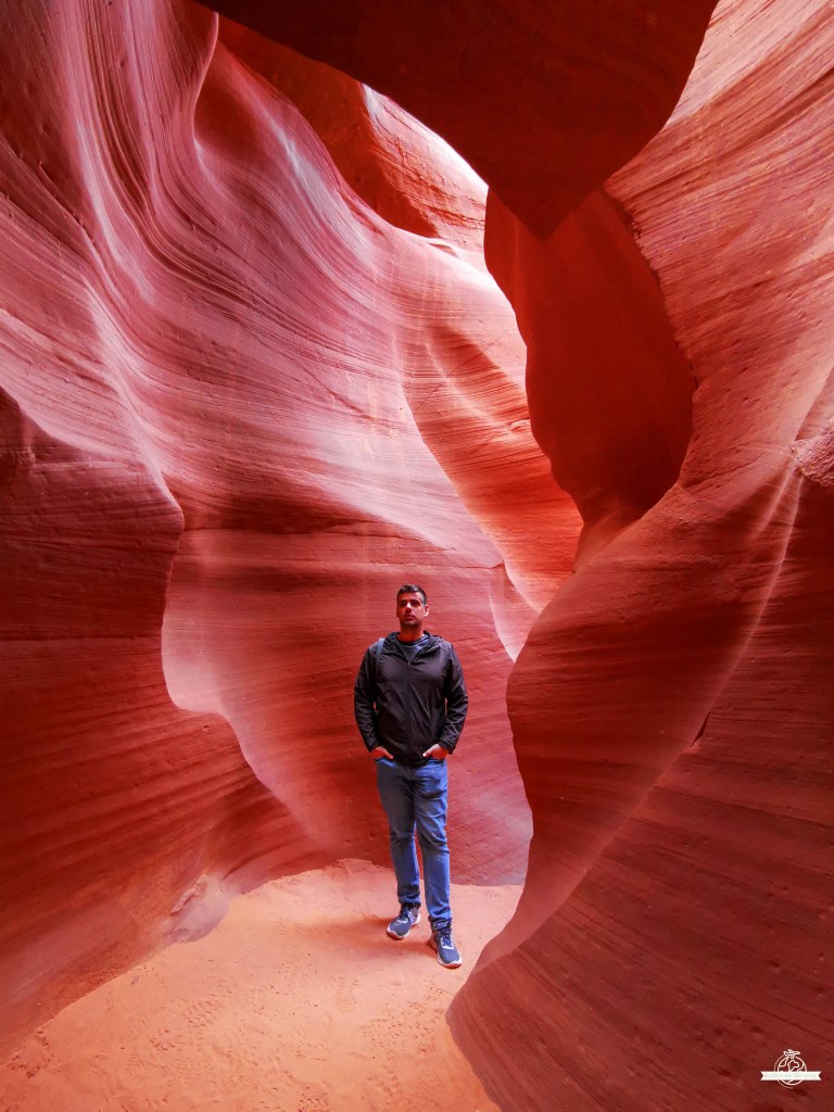 Visitor standing inside Antelope Canyon surrounded by red sandstone walls in Page, Arizona