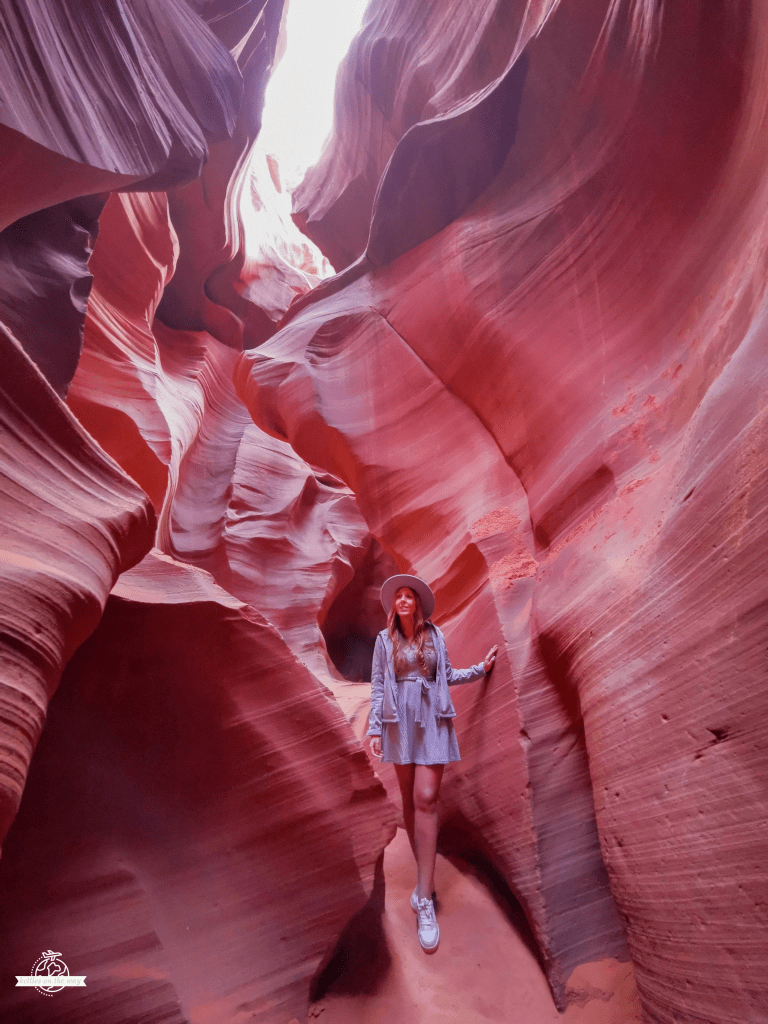 Woman standing among high red sandstone walls inside Antelope Canyon