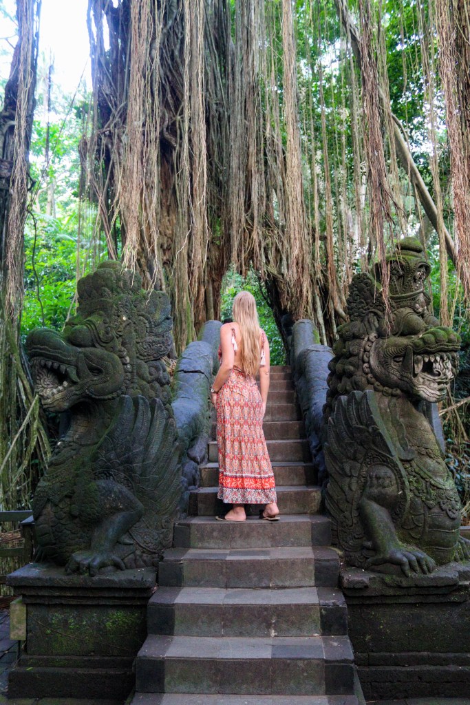 Zwiedzanie Monkey Forest w Ubud – praktyczny przewodnik po Małpim Lesie Kamienne schody mostku z rzeźbami i wielkim drzewem w Monkey Forest w Ubud na Bali