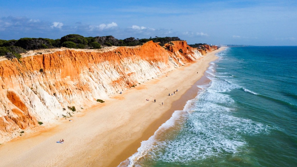 Our Top 7 Beaches in the Algarve Panoramic view of Praia da Falésia with orange cliffs, wide beach and waves