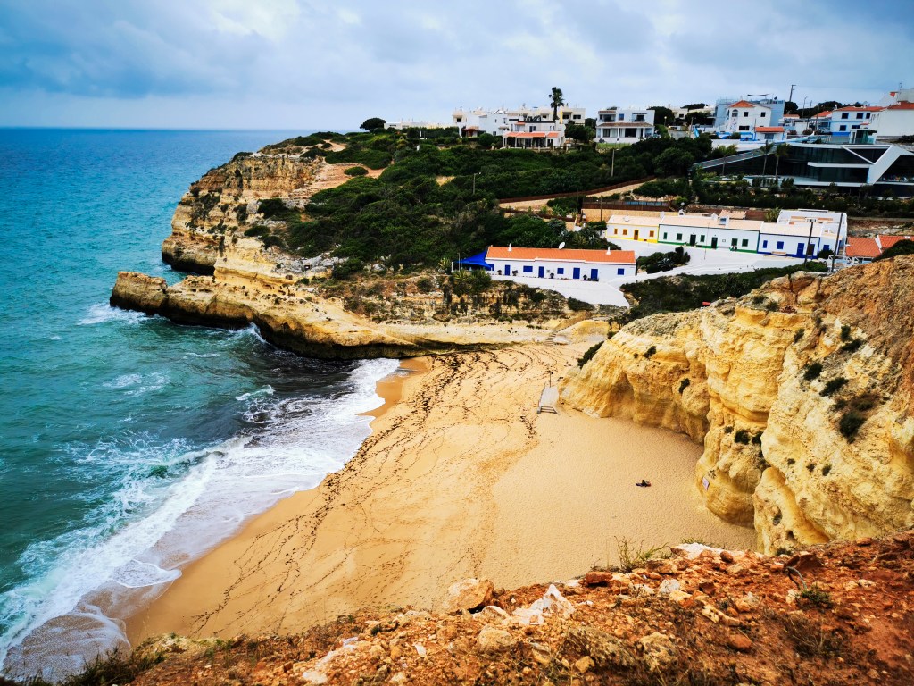 Our Top 7 Beaches in the Algarve View over Praia de Benagil with sandy beach, cliffs and white houses in the village above