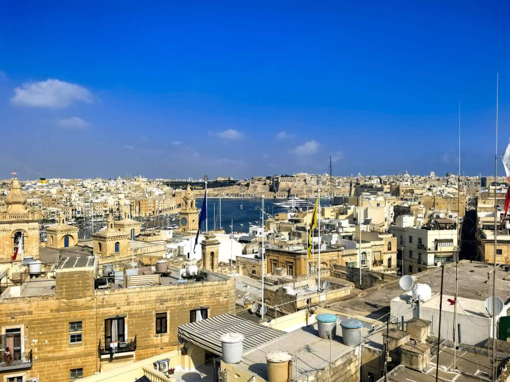 A Guide to Malta’s Three Cities: Discover Birgu, Isla and Bormla Panoramic rooftop view from a terrace in Birgu overlooking the historic limestone buildings and the Grand Harbour in Malta.