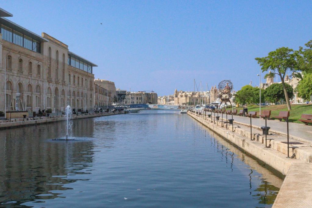 A Guide to Malta’s Three Cities: Discover Birgu, Isla and Bormla The revitalized Bormla (Cospicua) waterfront with a water fountain in Dockyard Creek and the American University of Malta building.