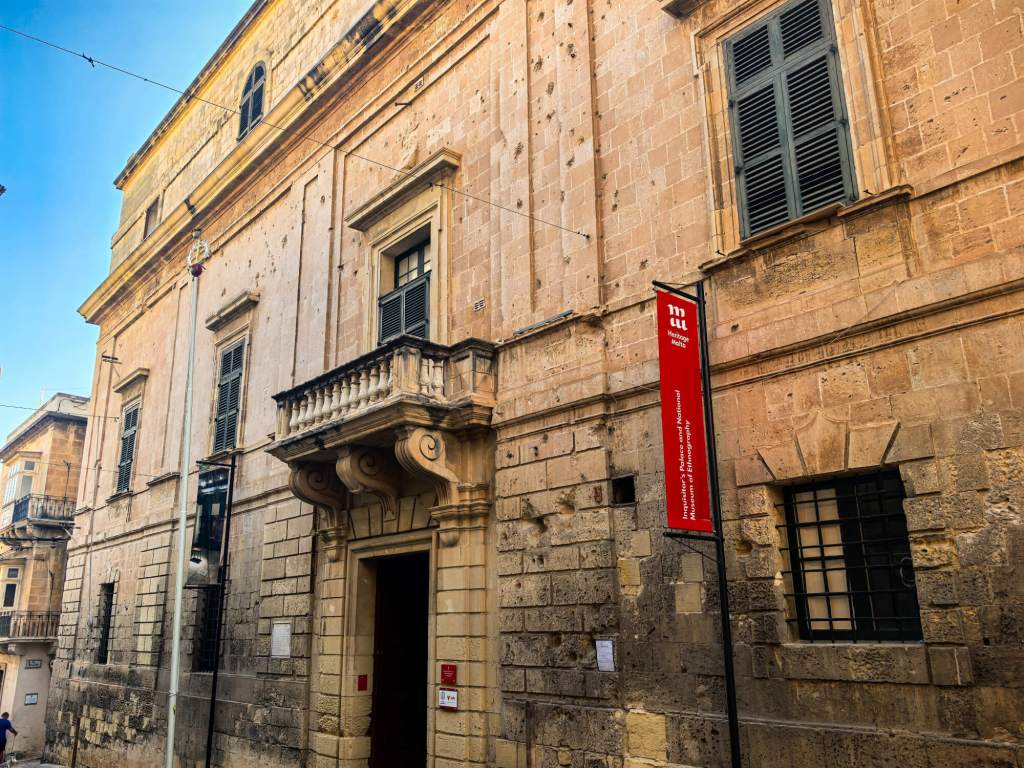 A Guide to Malta’s Three Cities: Discover Birgu, Isla and Bormla The historic limestone facade of the Inquisitor's Palace in Birgu, Malta, featuring the Heritage Malta banner.