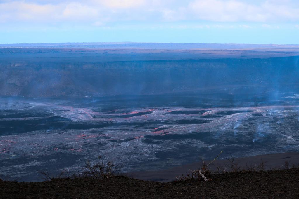 Rozległe pola lawy wulkanu Kīlauea z widocznymi oparami gazów wulkanicznych.