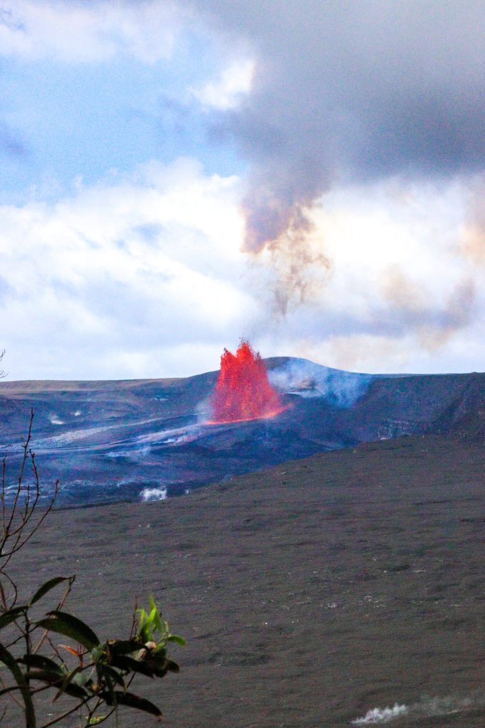 Erupcja Kīlauea na żywo: Jak zaplanować oglądanie lawy na Hawajach? (2026) Pionowe ujęcie erupcji Kīlauea z fontanną lawy i pióropuszem gazów nad kraterem.