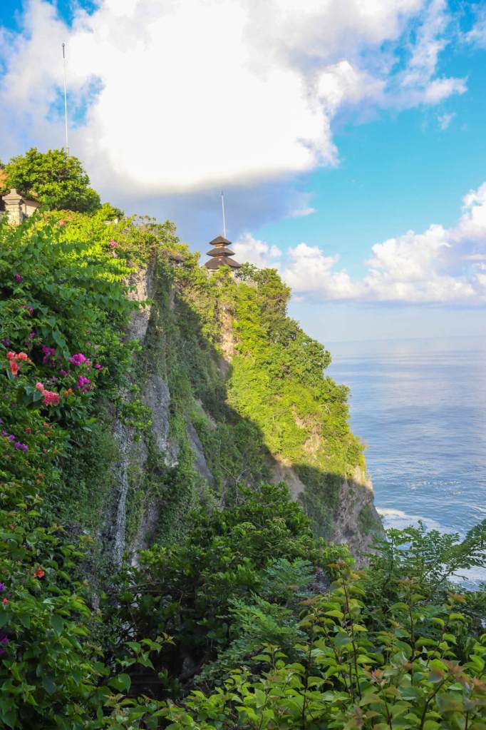 Świątynia Uluwatu, Bali – Kompletny przewodnik Trzypiętrowa pagoda w Pura Luhur Uluwatu na skraju klifu porośniętego roślinnością.