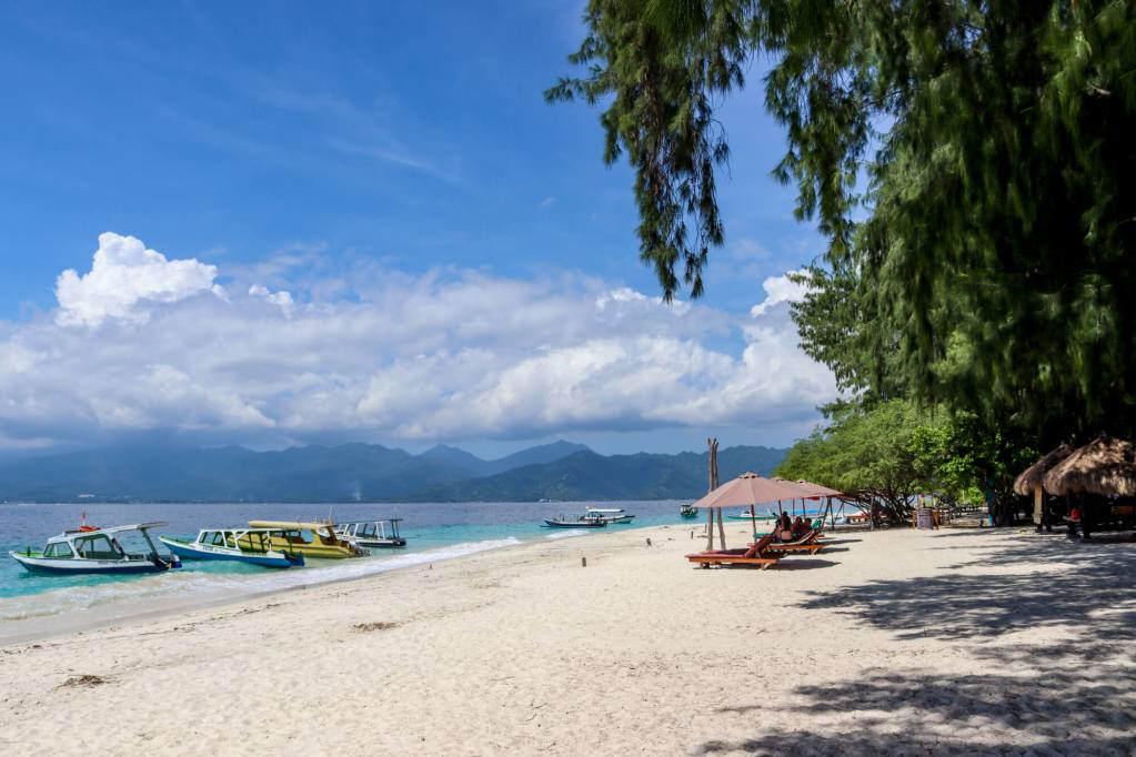 Rajskie wyspy Gili - informacje praktyczne Plaża na wyspach Gili z leżakami, łodziami i widokiem na Lombok
