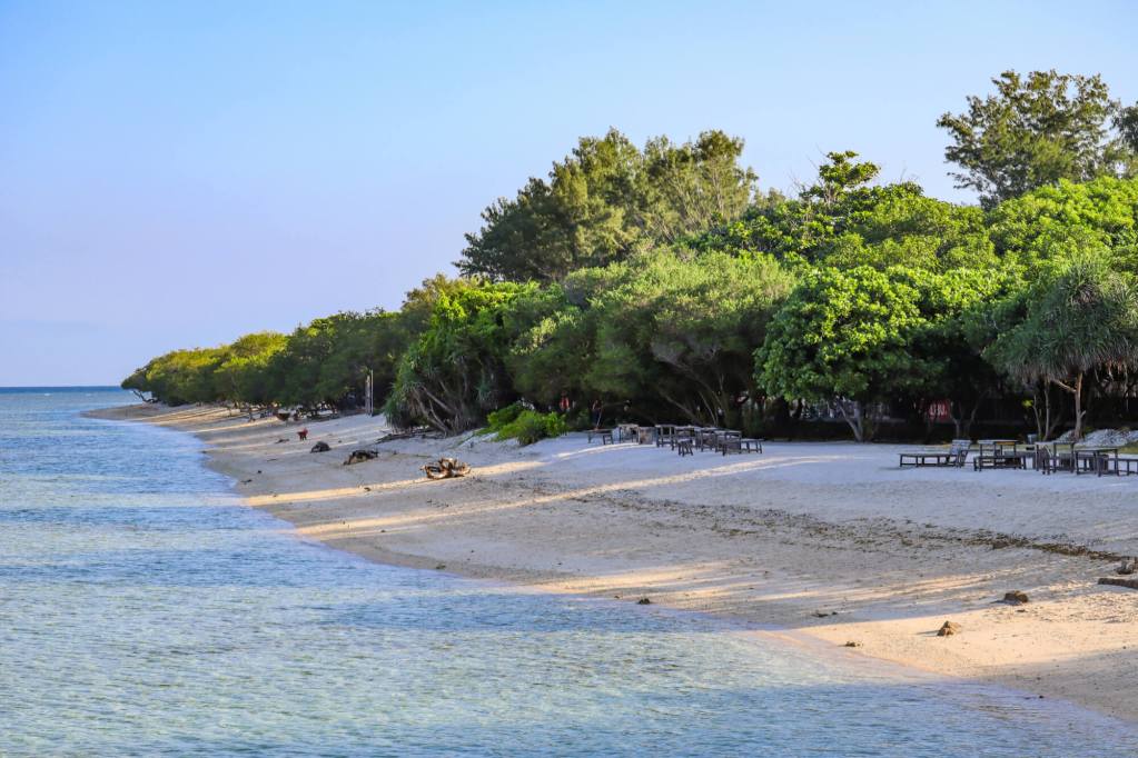Spokojna plaża z białym piaskiem i turkusową wodą na wyspach Gili