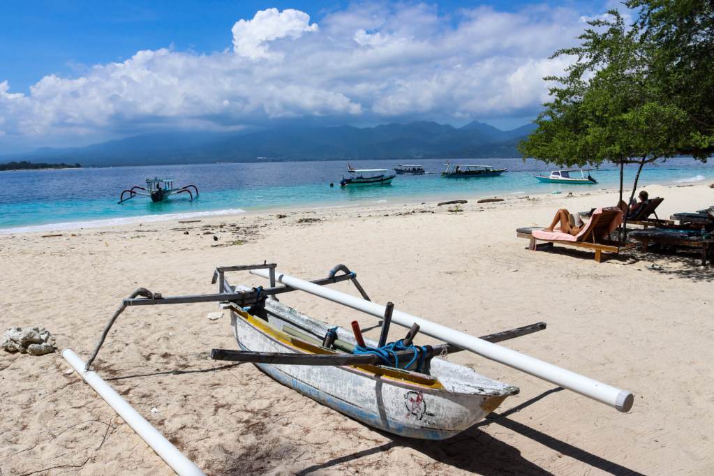 Tradycyjna łódź na plaży na wyspach Gili z widokiem na Lombok