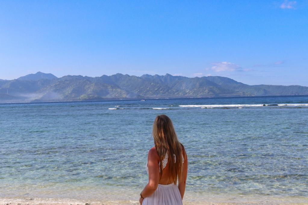 Rajskie wyspy Gili - informacje praktyczne Kobieta stojąca na plaży na wyspach Gili i patrząca w stronę Lomboku