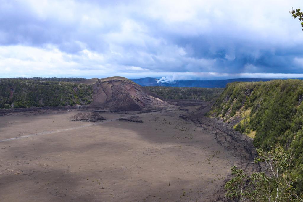A view of the Kīlauea Iki volcanic crater floor and cone, enclosed by green slopes in Hawaiʻi Volcanoes National Park.